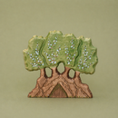 Wooden tree-shaped ornament with green leaves and brown trunk on a beige background