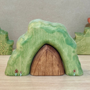 Green rock-like structure with a wooden door on a neutral background