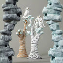 Decorative sculptures resembling trees and rocks with small figures on a neutral background