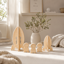 Wooden rocket and astronaut figures on a table with a vase of plants in the background.