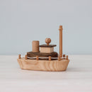 Handmade wooden toy boat with visible natural wood grain, featuring a simple yet detailed design with a captain's deck and a mast.