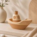 Wooden toy boat on a neutral background with a vase and plant