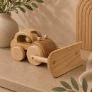 Wooden toy car on a beige surface with a plant in the background