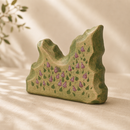 Green wooden sculpture with floral design on a beige surface