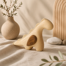 Wooden dinosaur toy on a textured surface with a vase and plants in the background