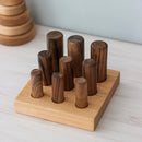 A wooden Montessori sorter with varying sized cylinders on a wooden base, placed on a white surface.