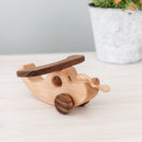 A small handcrafted wooden toy plane with wheels, made from ash, walnut and beech wood, placed on a wooden surface.