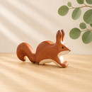 Wooden squirrel figurine on a wooden surface with a natural background