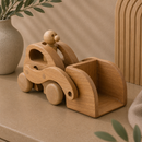Wooden toy car with a small figure on a beige surface with decorative elements.