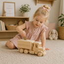Child playing with a wooden toy truck in a cozy room.