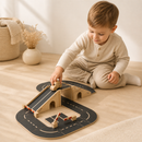Child playing with a wooden toy track set on a wooden floor.