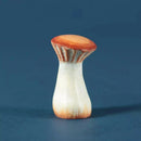A small mushroom-shaped object with a warm orange-brown cap and stem, fading to off-white toward the base, photographed on a smooth dark blue background.