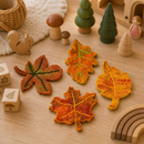 Felt leaf toys on a wooden surface with other toys and decorations.