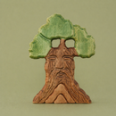 wooden tree with face carving in trunk and green leaves on a green background