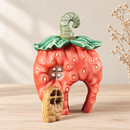 Noelino Wooden Strawberry Fairy House with its wooden door beside the open doorway.