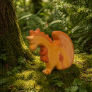 Wooden dragon toy on a mossy forest floor