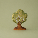 Wooden tree figurine with green foliage and brown trunk on a green background