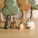 group of various wooden toy rabbits with wooden trees in the background