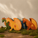 Four different coloured dragons standing together on mossy ground